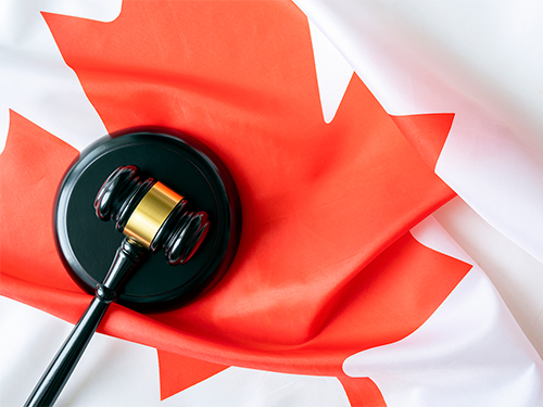A gavel resting on a Canadian flag.