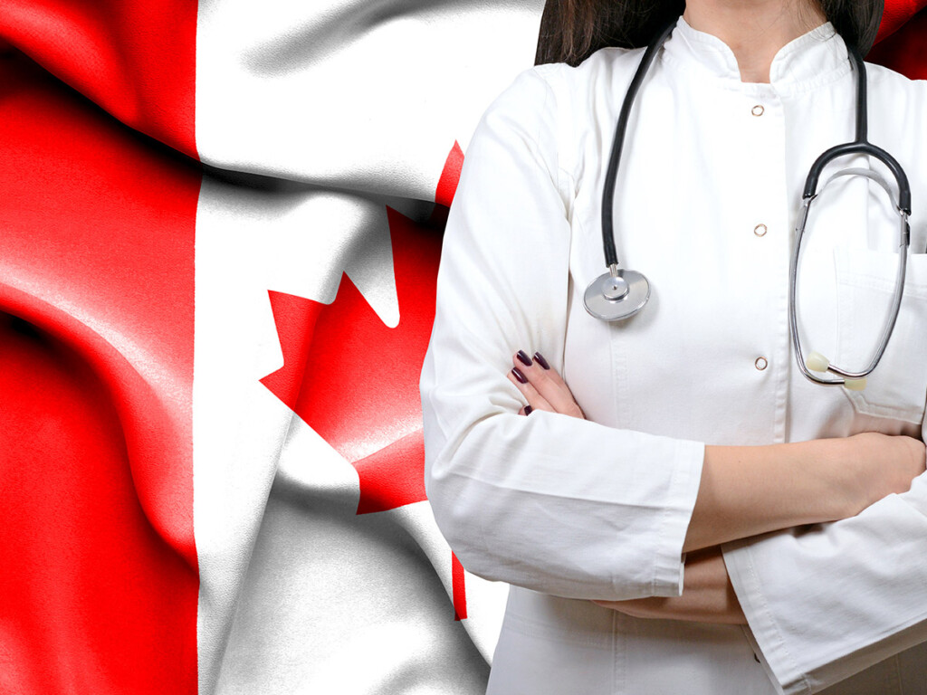 A physician standing in front of the flag of Canada.