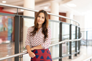 A woman poses for a photo while leaning against a railing.