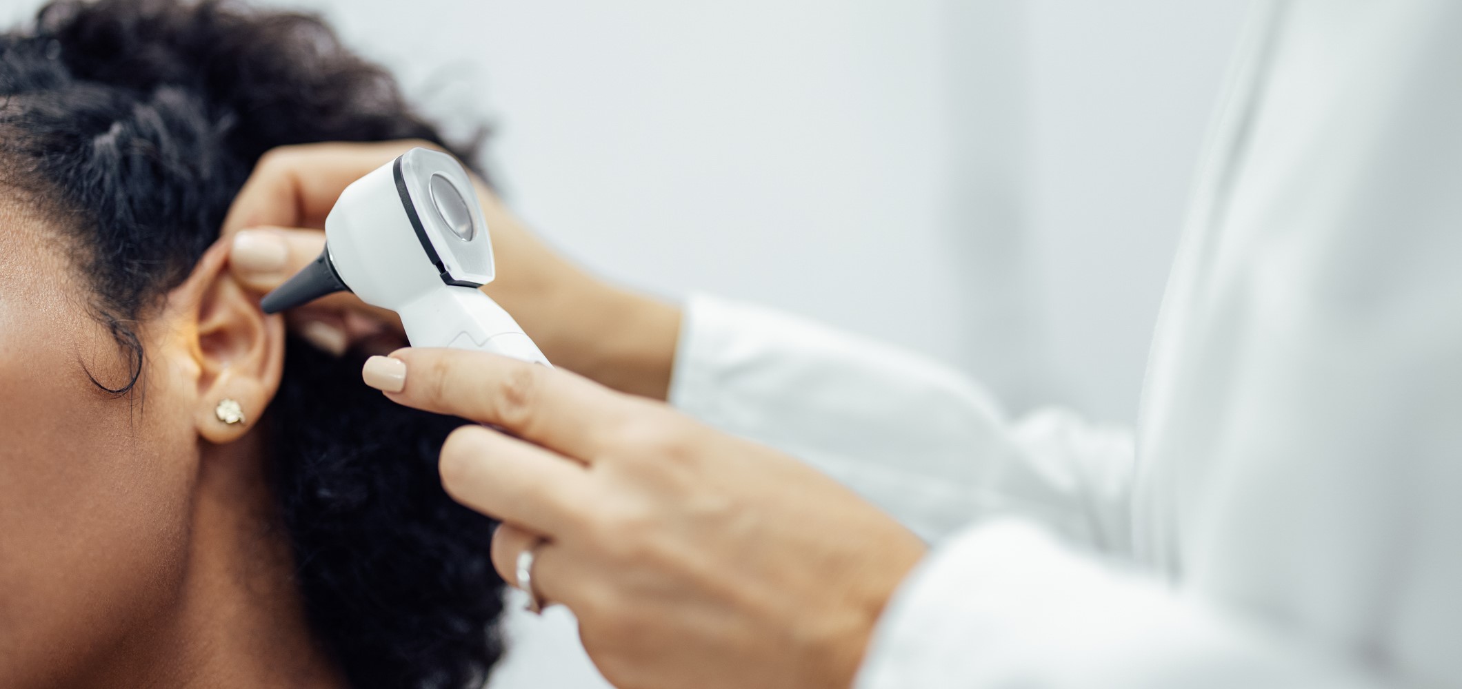 A woman having her ear looked at by a doctor