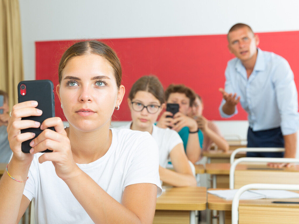 A student holds a smartphone in a classroom
