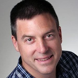 A headshot of a main in a plaid button up shirt