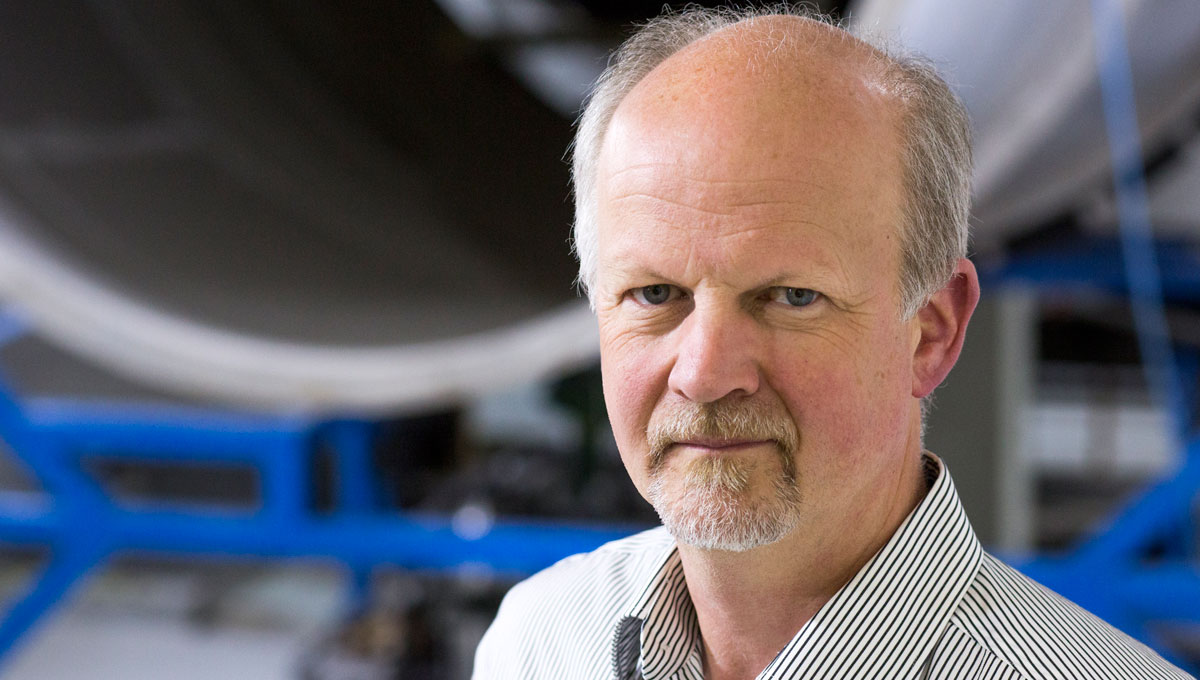 A headshot of a man wearing a stripped dress shirt.