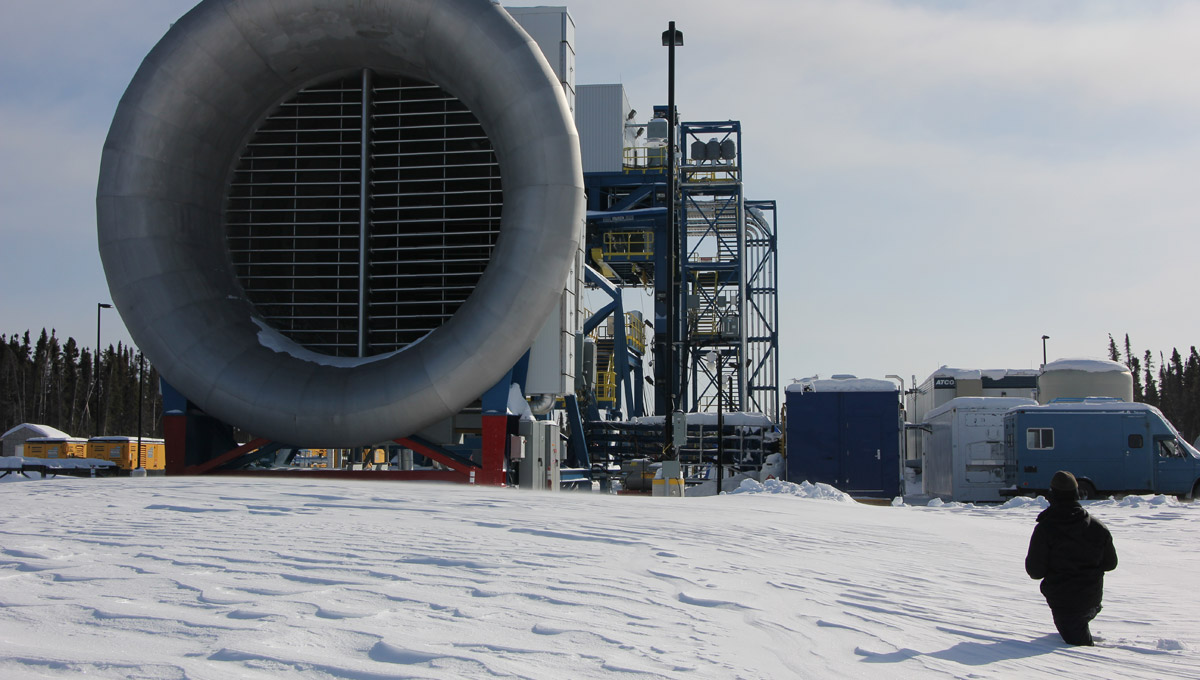 A man walks through the snow towards a large machine used for aerospace research.
