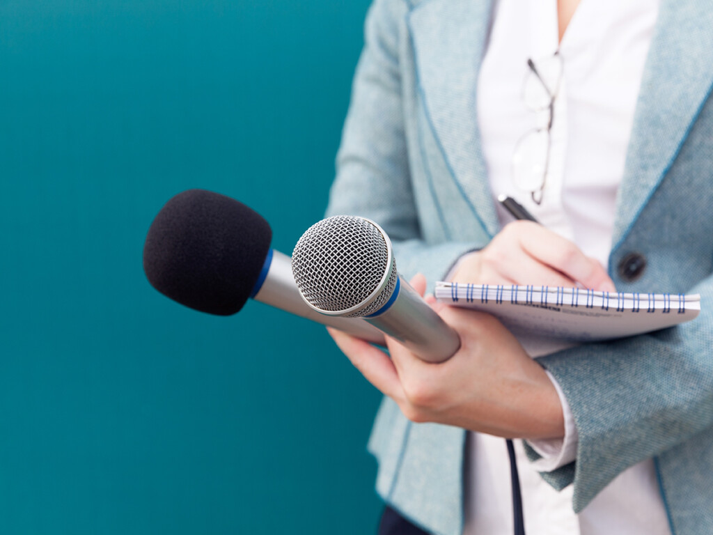 A journalist holding a microphone and notepad