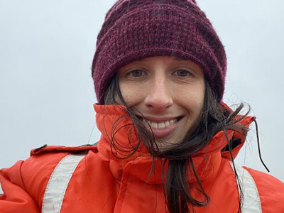 A woman with bright orange jacket and a mauve hat.