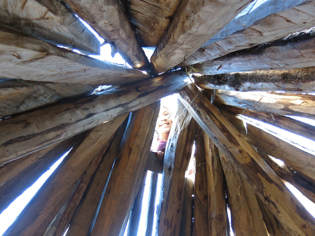 A child looking through the top of a teepee