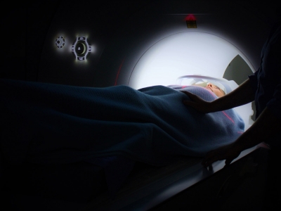 A patient in an MRI machine is monitored in a dark room.