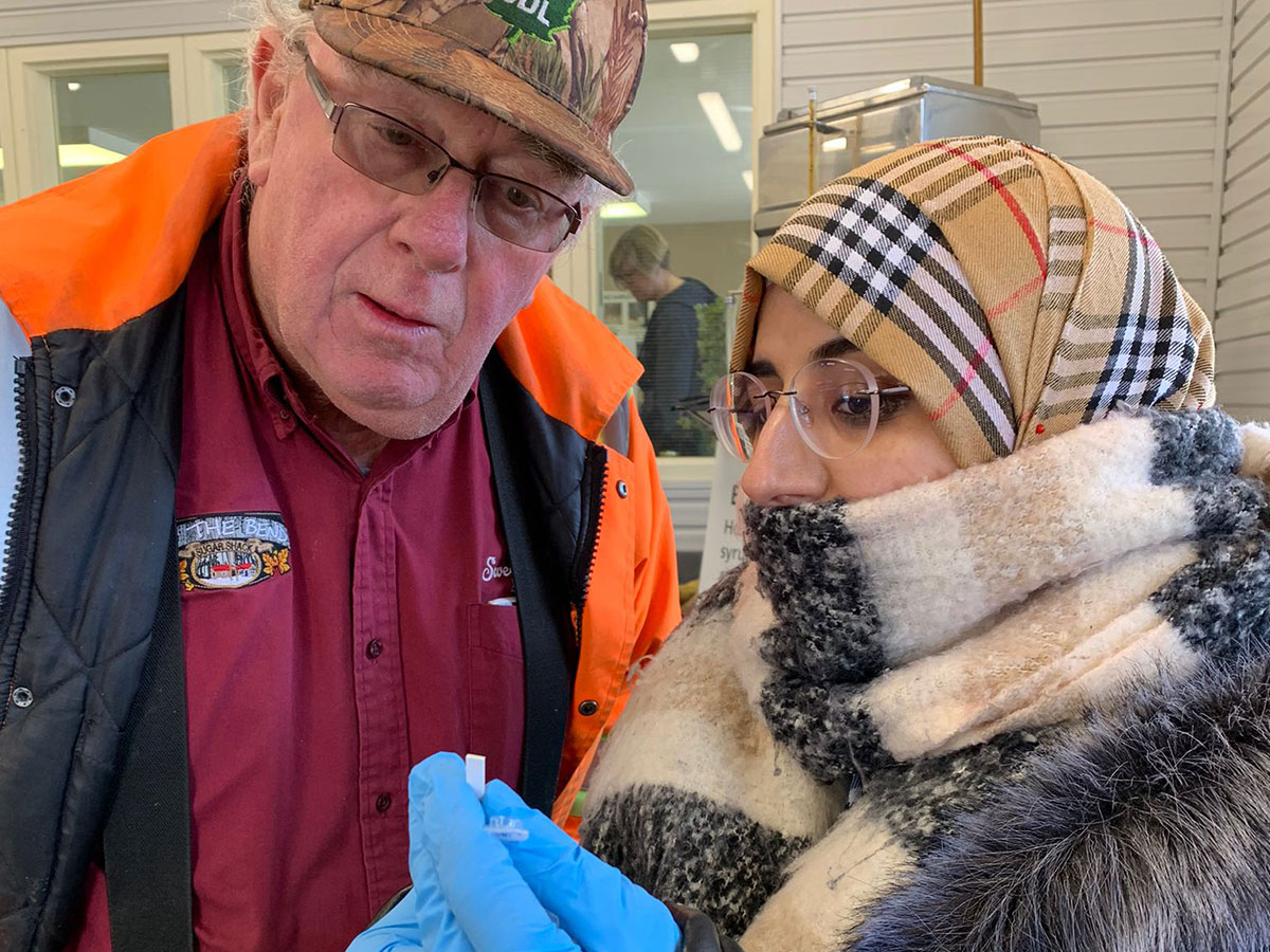 Two people looking at a buddy sap from maple syrup production.