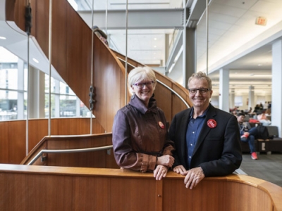 Martha Attridge Bufton and David Dean pose by the spiral staircase in the MacOdrum Library.