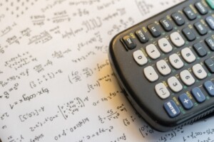 A calculator sits on a sheet of math equations.