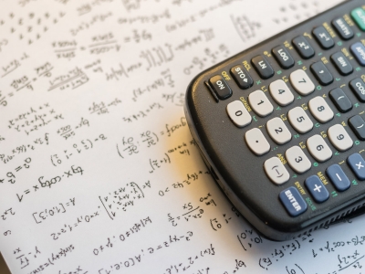 A calculator sits on a sheet of math equations.