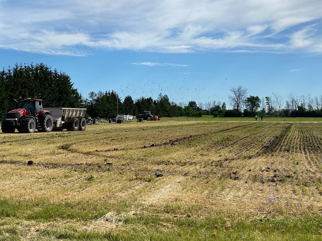 Biosolids being sprayed on an agricultural field by a large tractor.