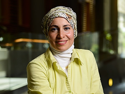 A headshot of Nadia Abu-Zahra in a spacious hallway.