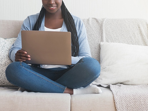 A woman uses a laptop while sitting on the couch