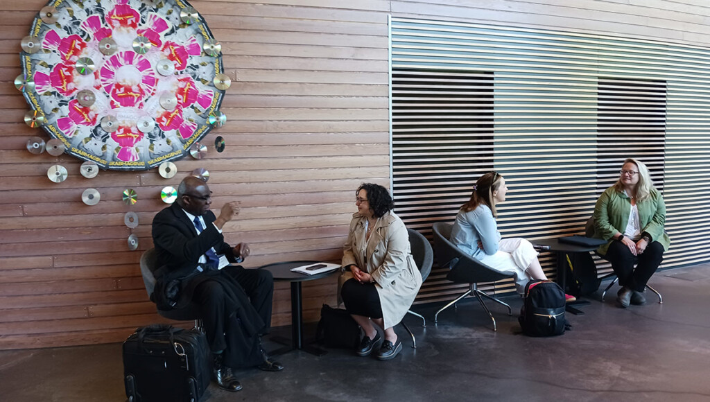 Two groups of two people sitting at coffee tables, having discussions.