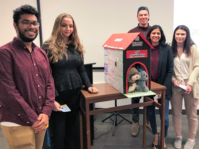 The winning group, called The Dogwalkers, pose while displaying a doghouse with messages written over it.