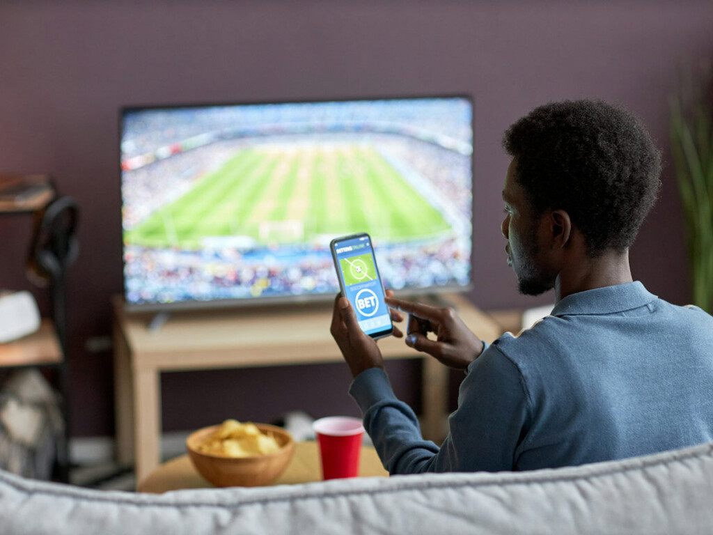 A man holding a mobile phone and taking part in online gambling.
