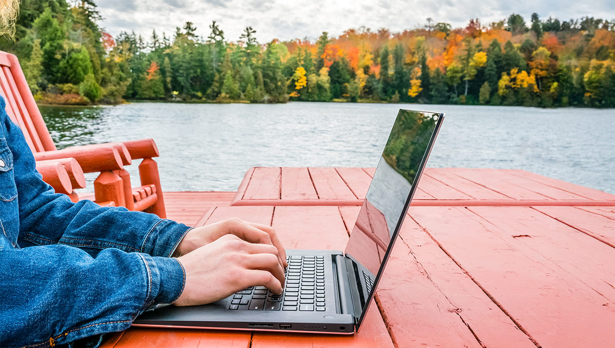 A person on a laptop in a rural area, representing the need for strong non-terrestrial networks.