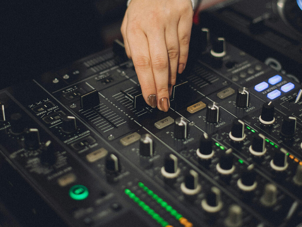 A hand can be seen adjusting a knob on a sound mixer.