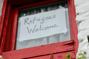 Sign on a window that says Refugees Welcome