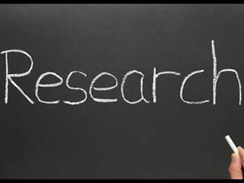 A hand holding chalk writes the word 