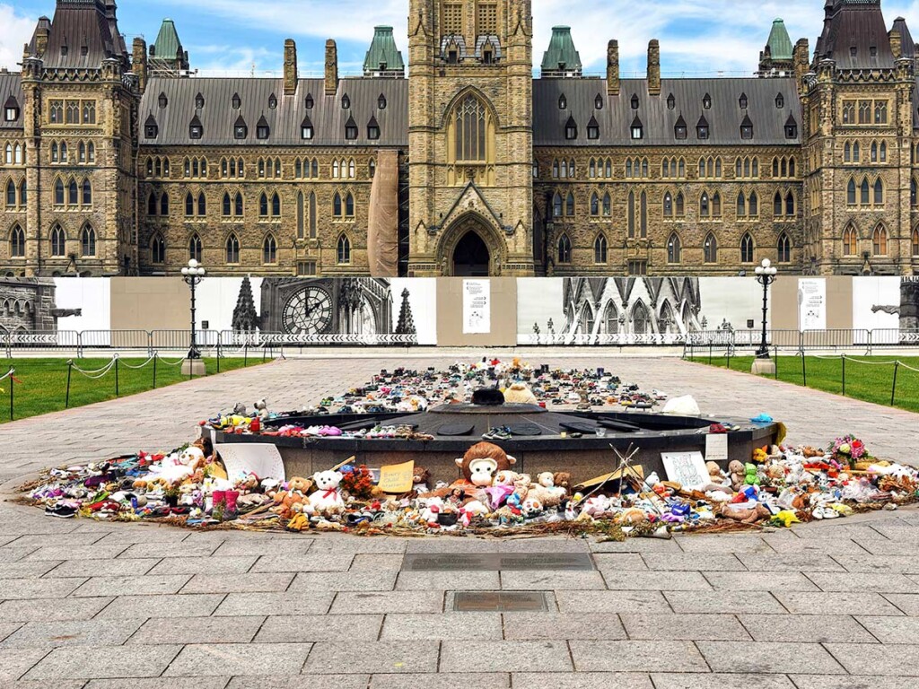 Shoes and toys surround the Centennial Flame on Parliament Hill in memory of the children whose remains were found near former Residential Schools.