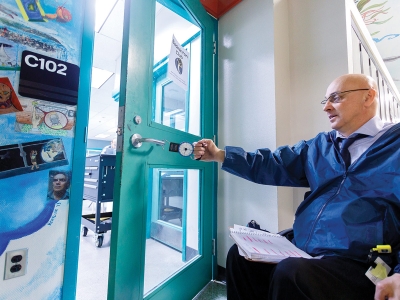 A person in a wheelchair opens a door with a measurement device.