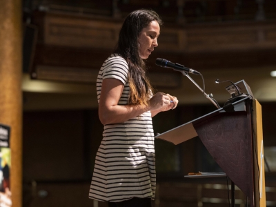A youth in a striped dress speaks at a podium in the sanctuary of the Dominion-Chalmers United Church.