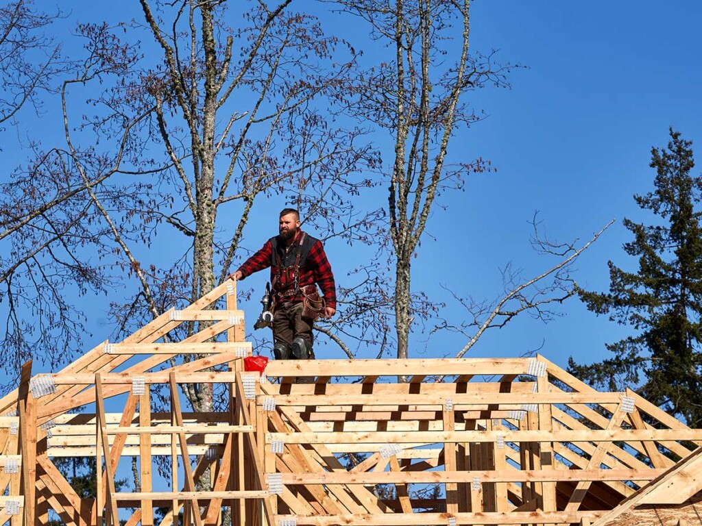 Construction worker on a framed in roof of a house under construction.