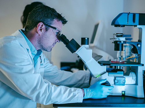A scientist looking into a microscope.