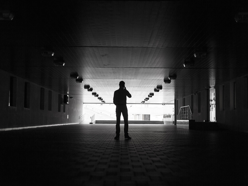 Whistleblowing concept. The silhouette of a man making a phone call in a dark hallway