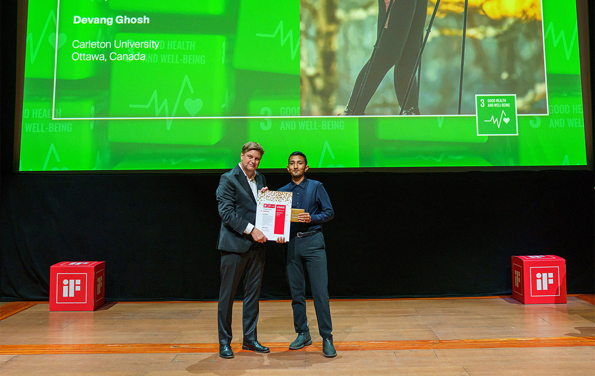 A student accepting an award for his design project SnowStride stands with a presenter to take a photo of the occasion.