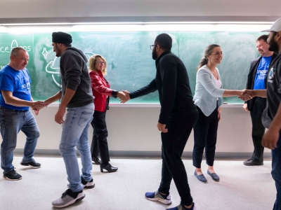 Carleton and Ottawa-area students shake hands near a blackboard at the conclusion of Space Apps Ottawa 2019.