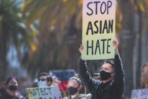 A man holds a sign that reads 'Stop Asian Hate'