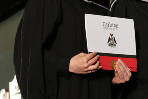 A gradute holding a degree while on stage during a convocation ceremony.