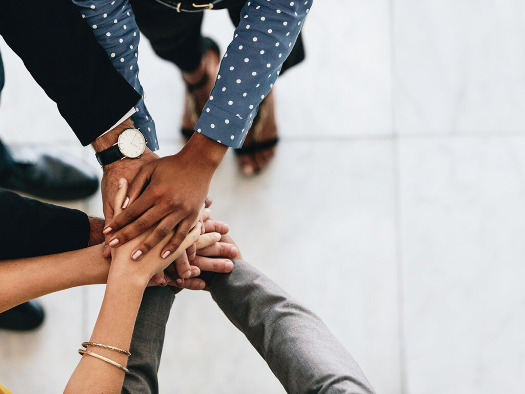 Various people putting their hands together