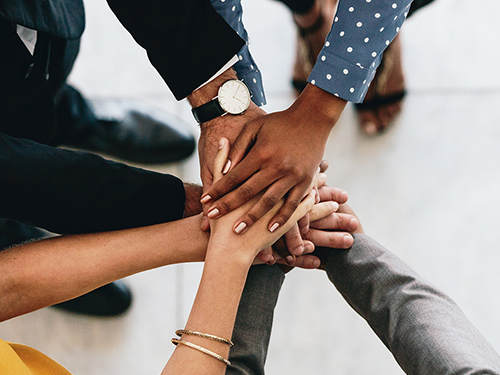 Various people putting their hands together