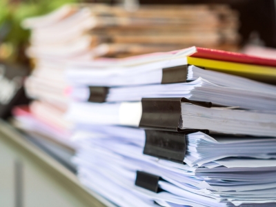 Piles of paper surveys sit on a desk.