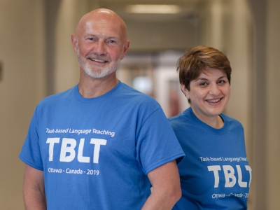 Profs. David Wood and Eva Kartchava pose in T-shirts emblazoned with the Conference on Task-Based Language Teaching conference wordmark.