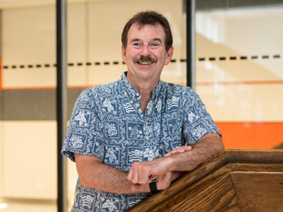 Tim Patterson poses in the lobby of the Steacie Building, with the Superlab visible in the background.
