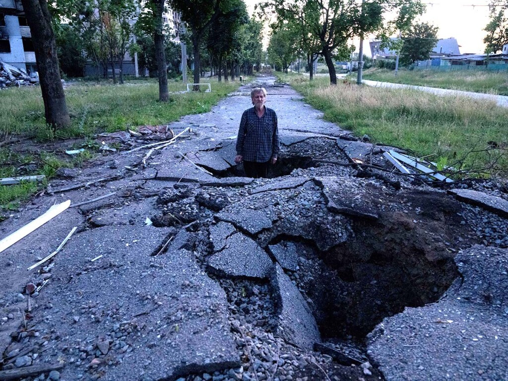 A man stands in a crater after a Russian attack in Kharkiv, Ukraine