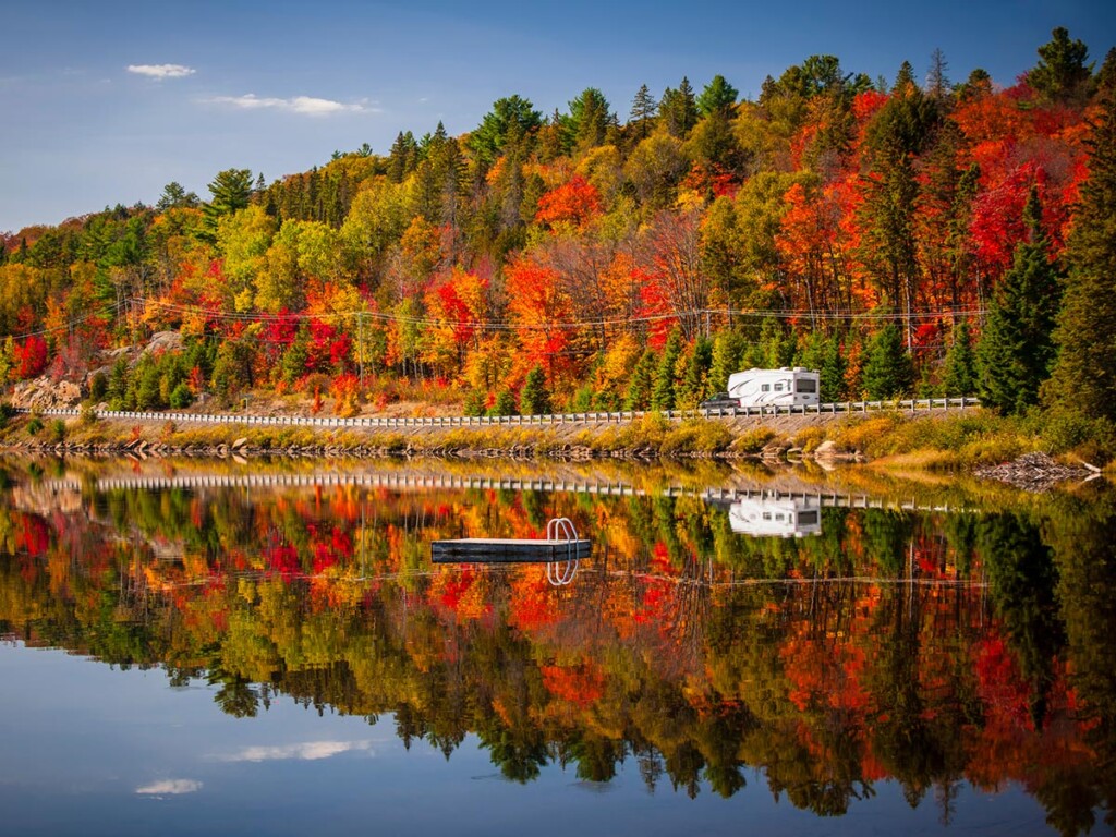 Fall forest with colorful autumn leaves and highway 60 reflecting in Lake of Two Rivers. Algonquin Park, Ontario, Canada