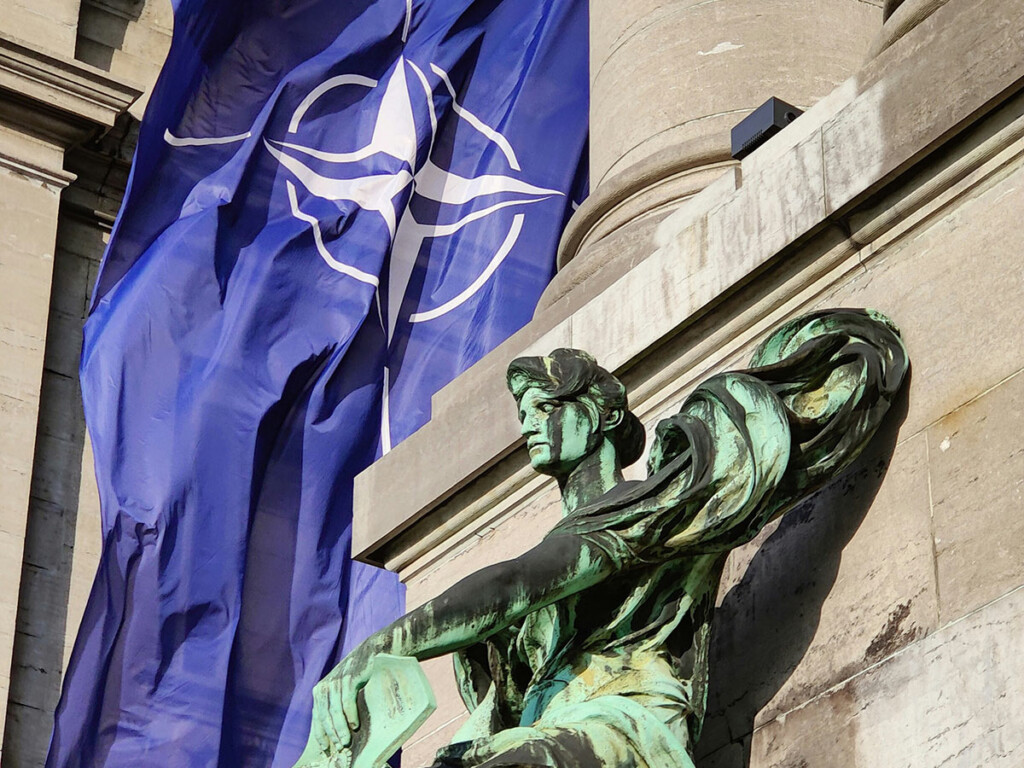 A NATO flag drapped over the side of a building.
