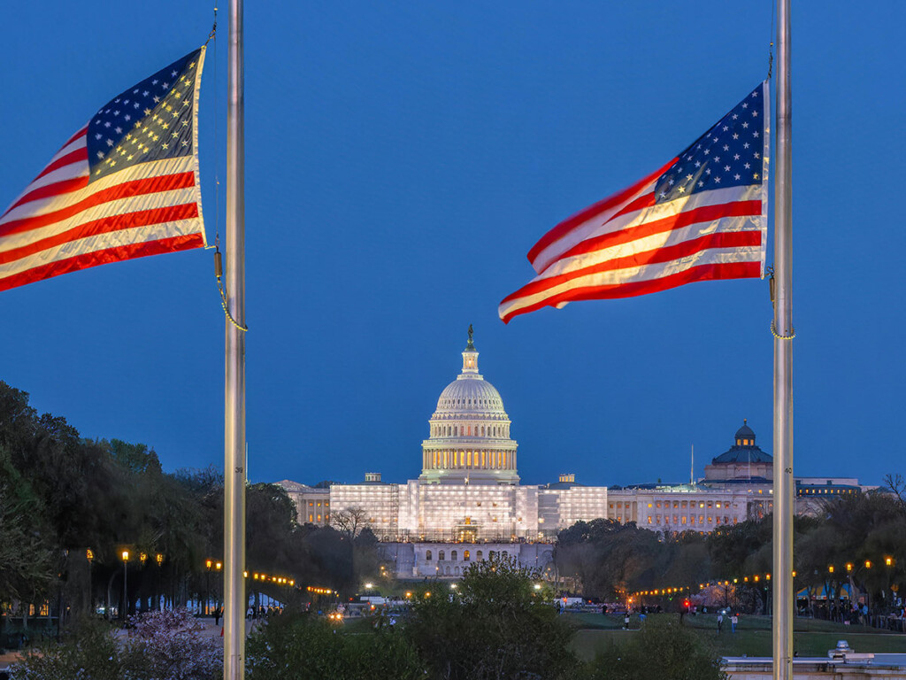 The U.S. Capitol Building with two American flags in front of it.