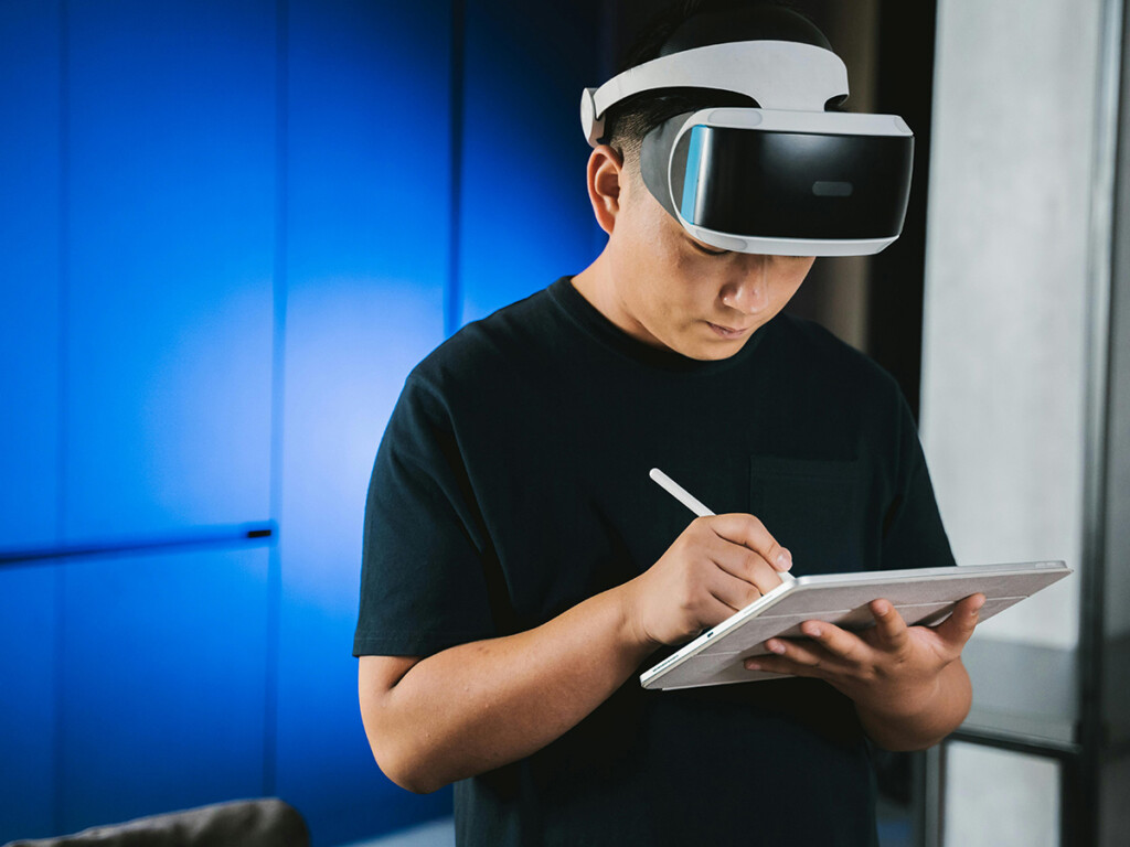 A man wearing a VR headset works on a tablet.