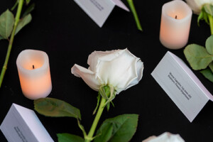 A white rose flanked by white candles