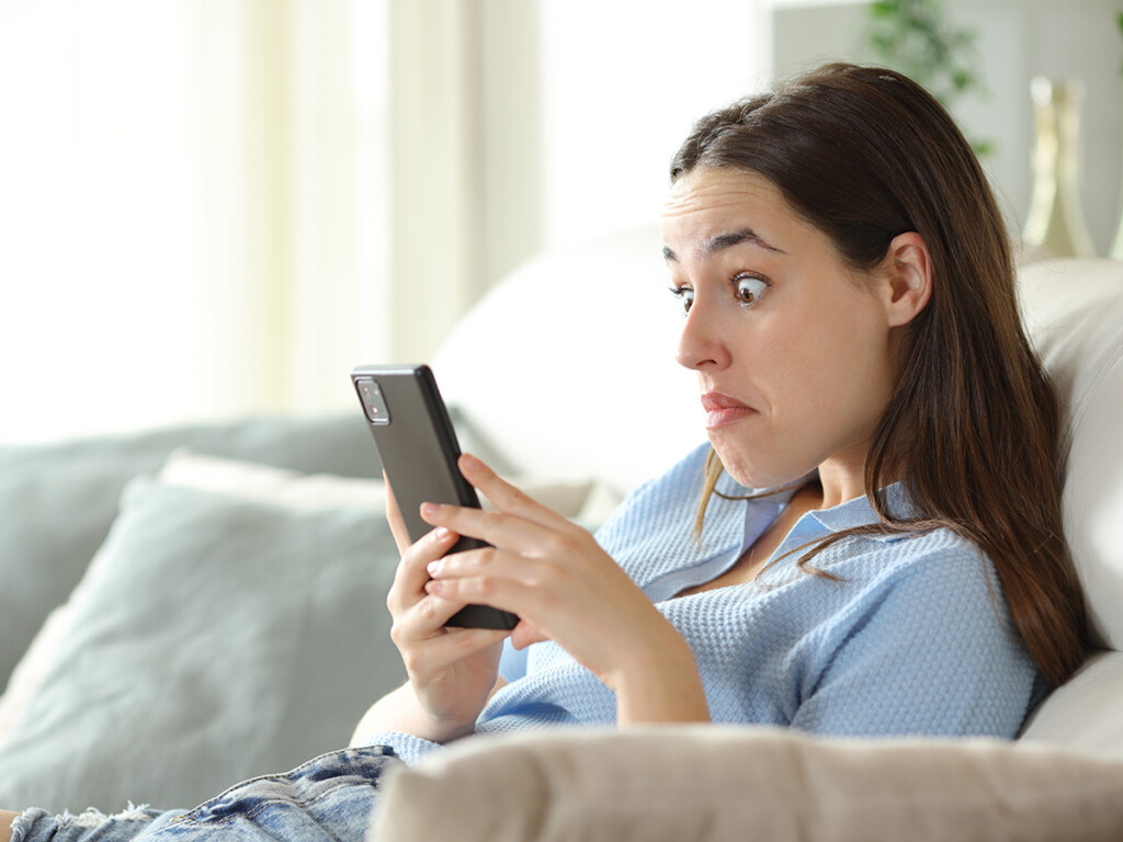 A woman reacts to memes about politics on her mobile phone.