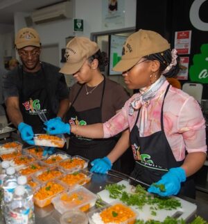 Volunteers serve curry and rice in a food kitchen.