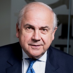 A man in a blue suit smiles at the camera.